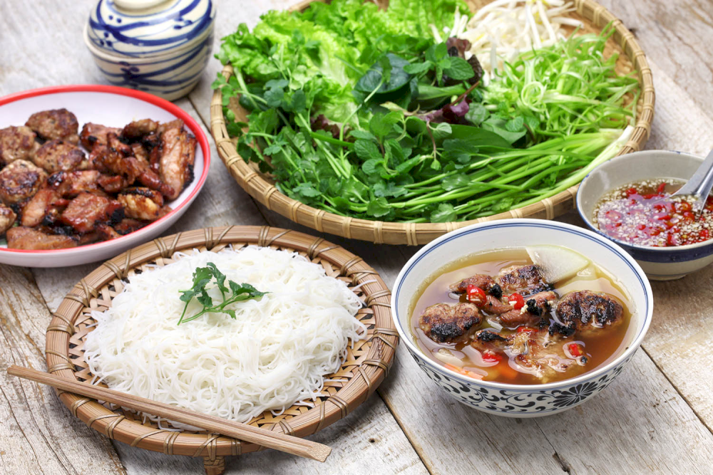 Bun Cha Hanoi consists of aromatic grilled pork, fresh vermicelli noodles, herbs, and a tangy-sweet dipping sauce